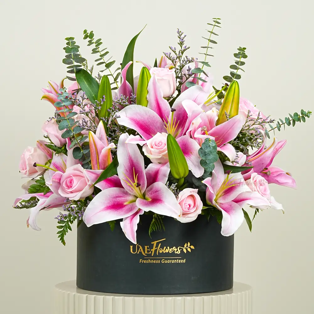 5 pink lilies and 12 pink roses with eucalyptus leaf and limonium fillers in a black box.