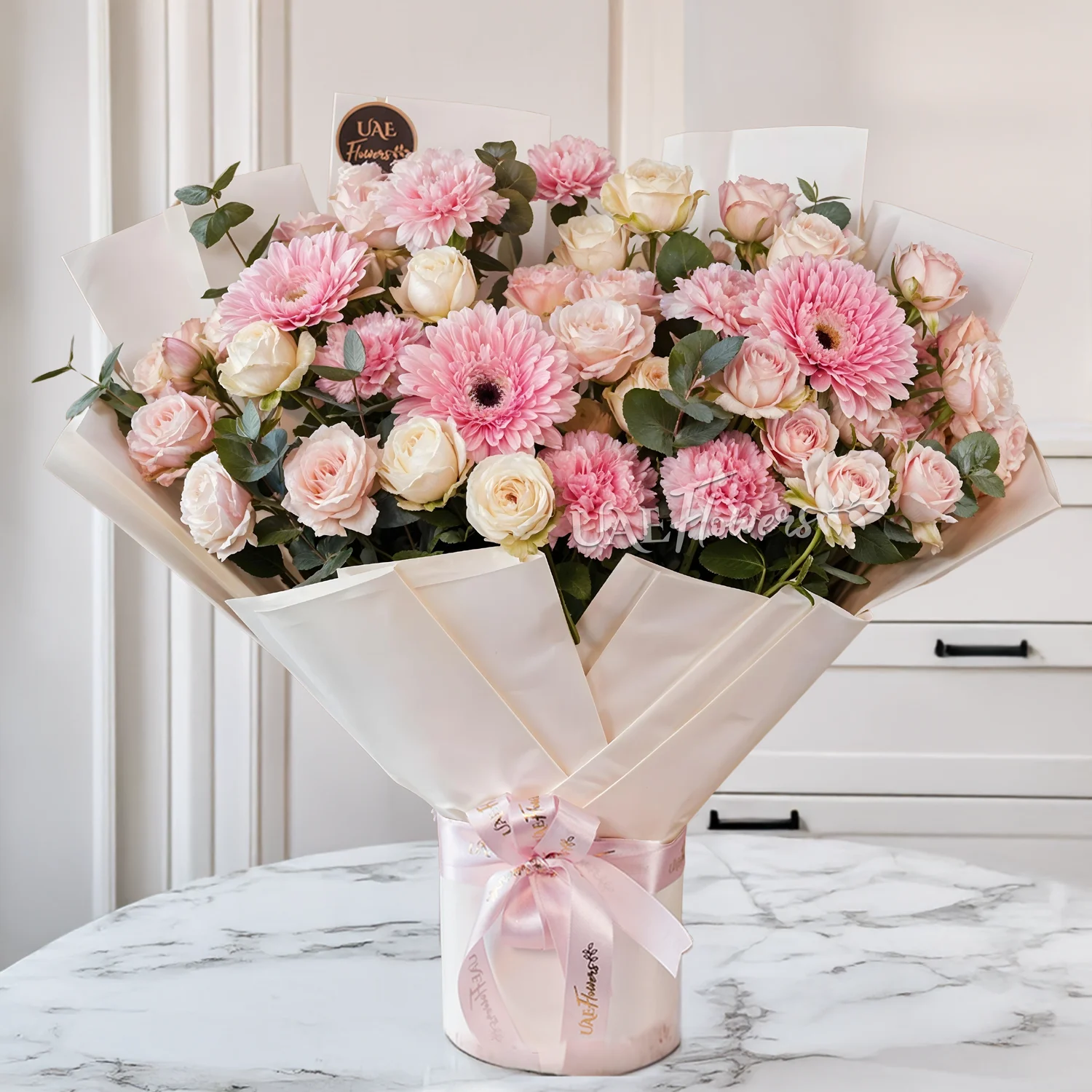 Bouquet of 4 pink gerberas, 6 pink carnations, 6 pink spray roses and 6 peach spray roses with green fillers tied with ribbons.