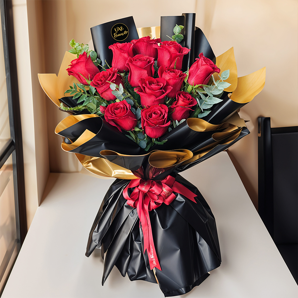Bouquet of 12 stems of red roses with green fillers beautifully wrapped in black and gold wrapping paper with red ribbon.