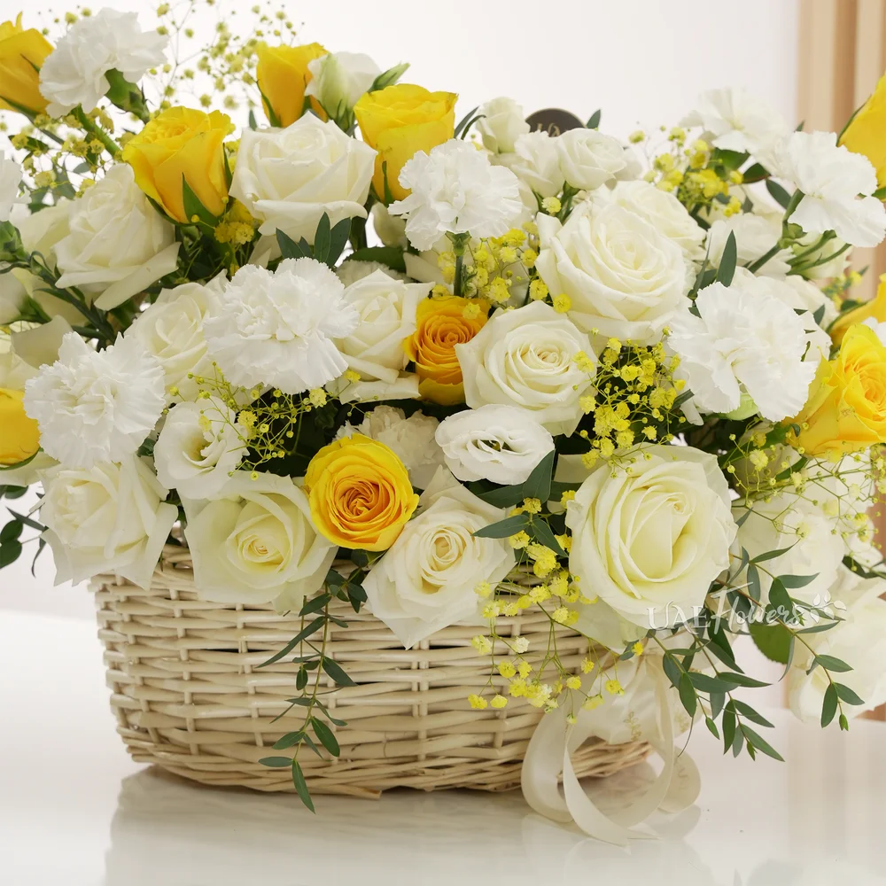 Basket arrangement of 20 yellow and white roses, 10 white carnations with green and yellow baby's breath fillers.
