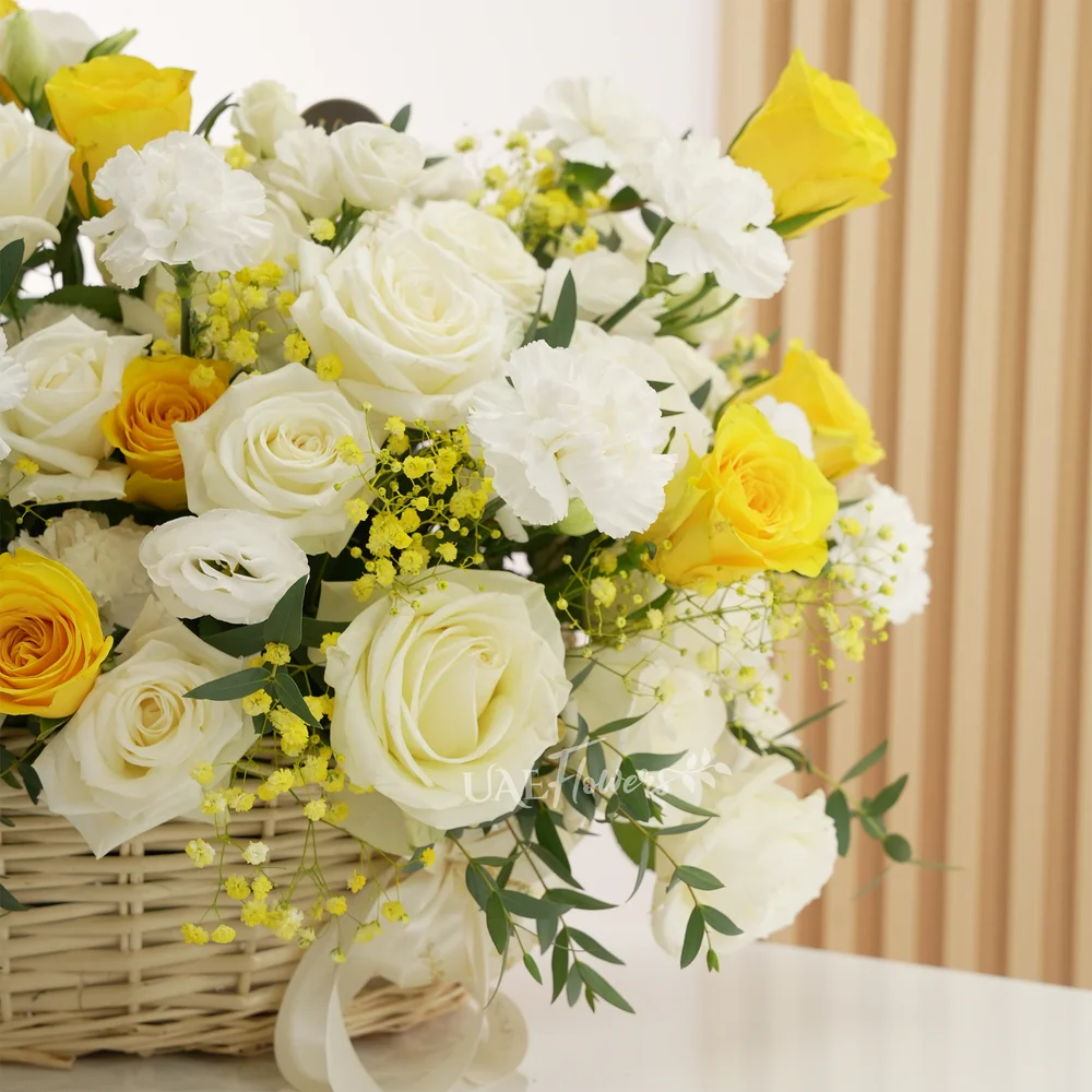 Basket arrangement of 20 yellow and white roses, 10 white carnations with green and yellow baby's breath fillers.