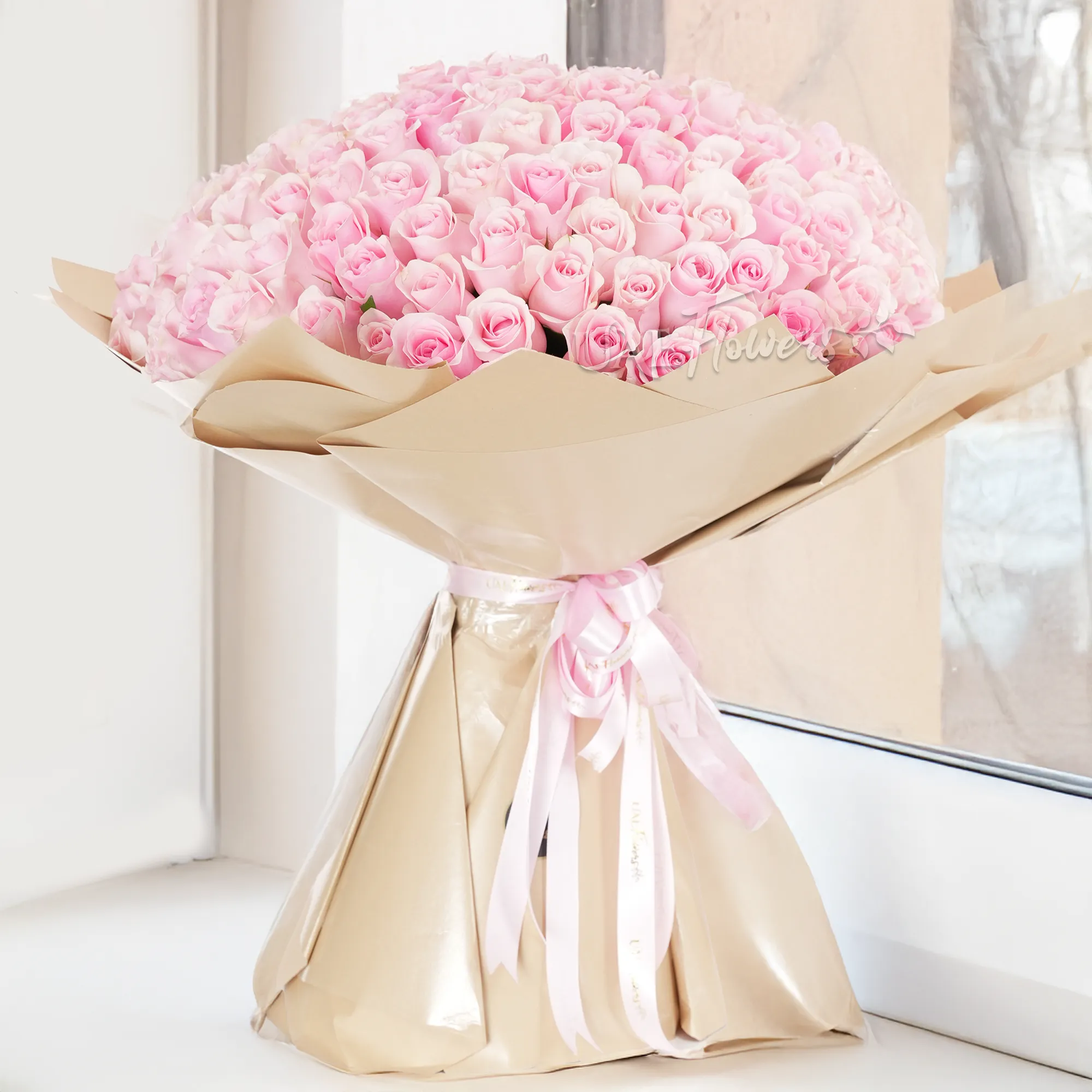Bouquet of 200 pink roses with fillers in brown paper packing tied with pink ribbons.