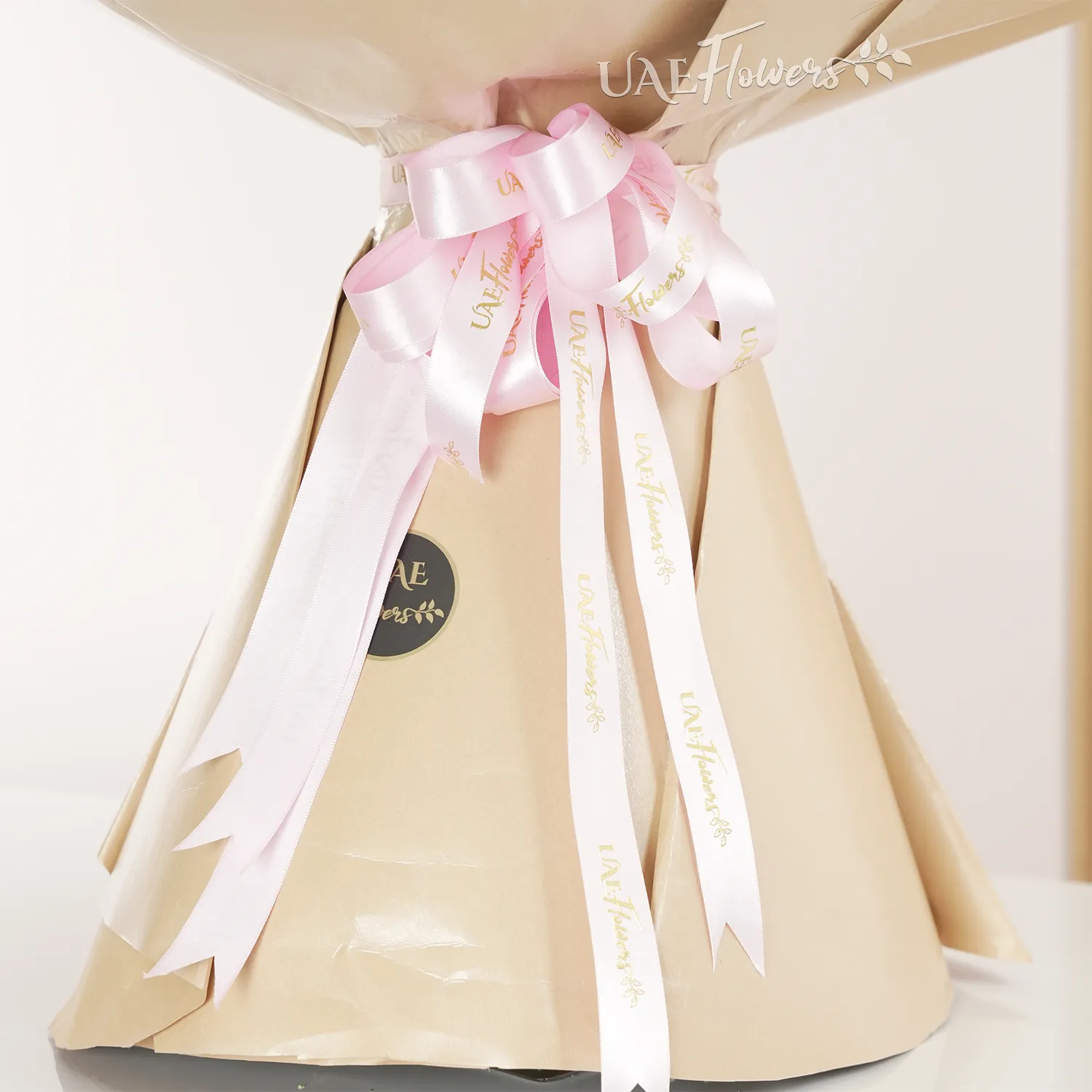 Bouquet of 200 pink roses with fillers in brown paper packing tied with pink ribbons.