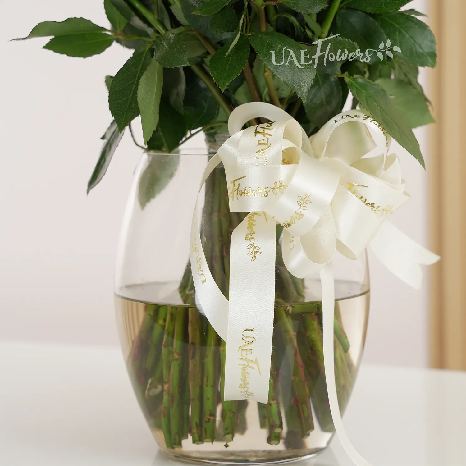 A vase arrangement of 40 white roses with green fillers tied with white ribbons.