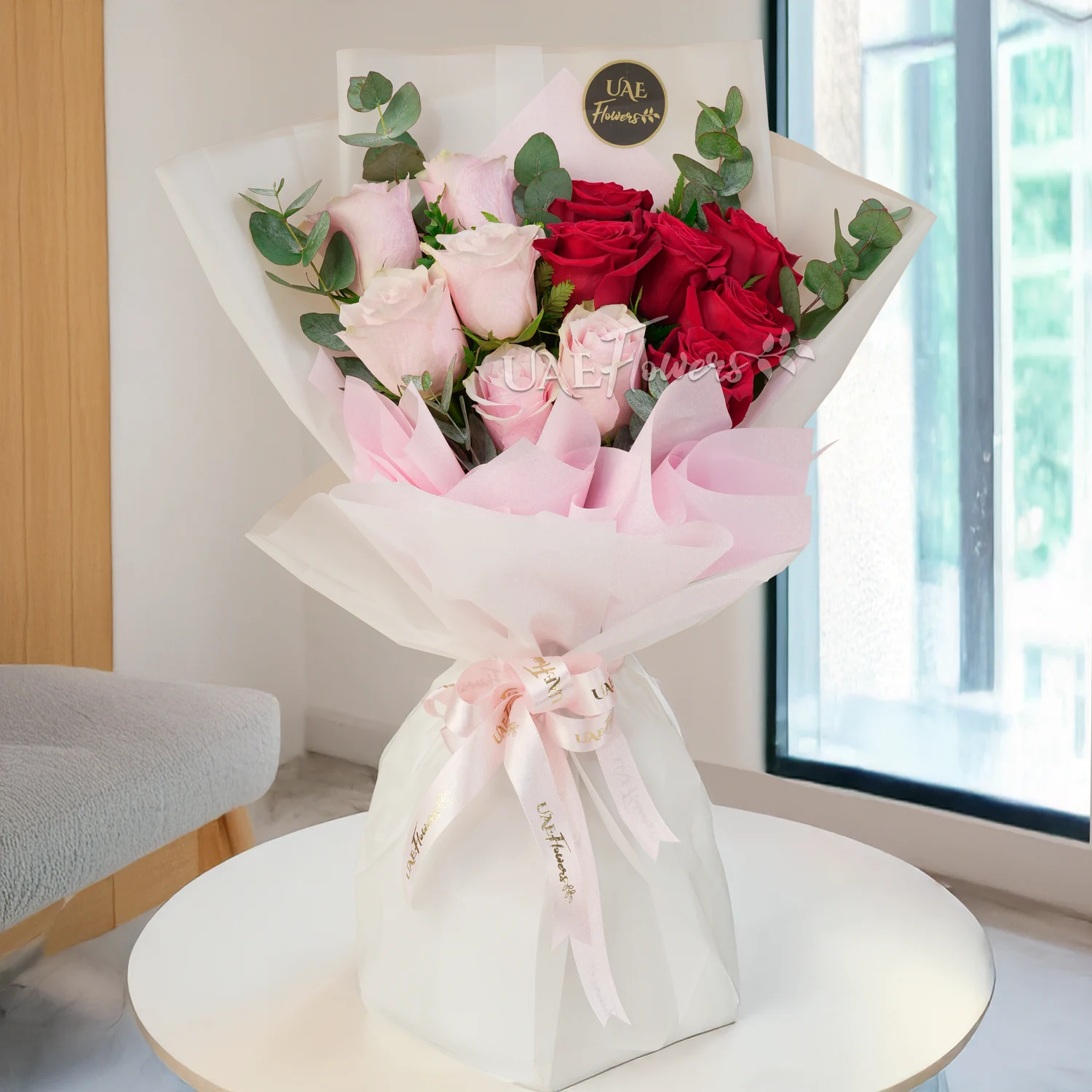 Bouquet of 6 red & 6 pink roses with green fillers in paper packing tied with pink ribbons.
