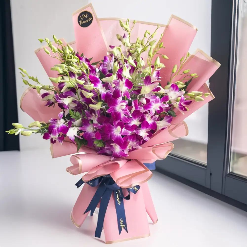 Bouquet of 30 stems of purple orchids with green fillers wrapped in pink paper packing with blue ribbons.