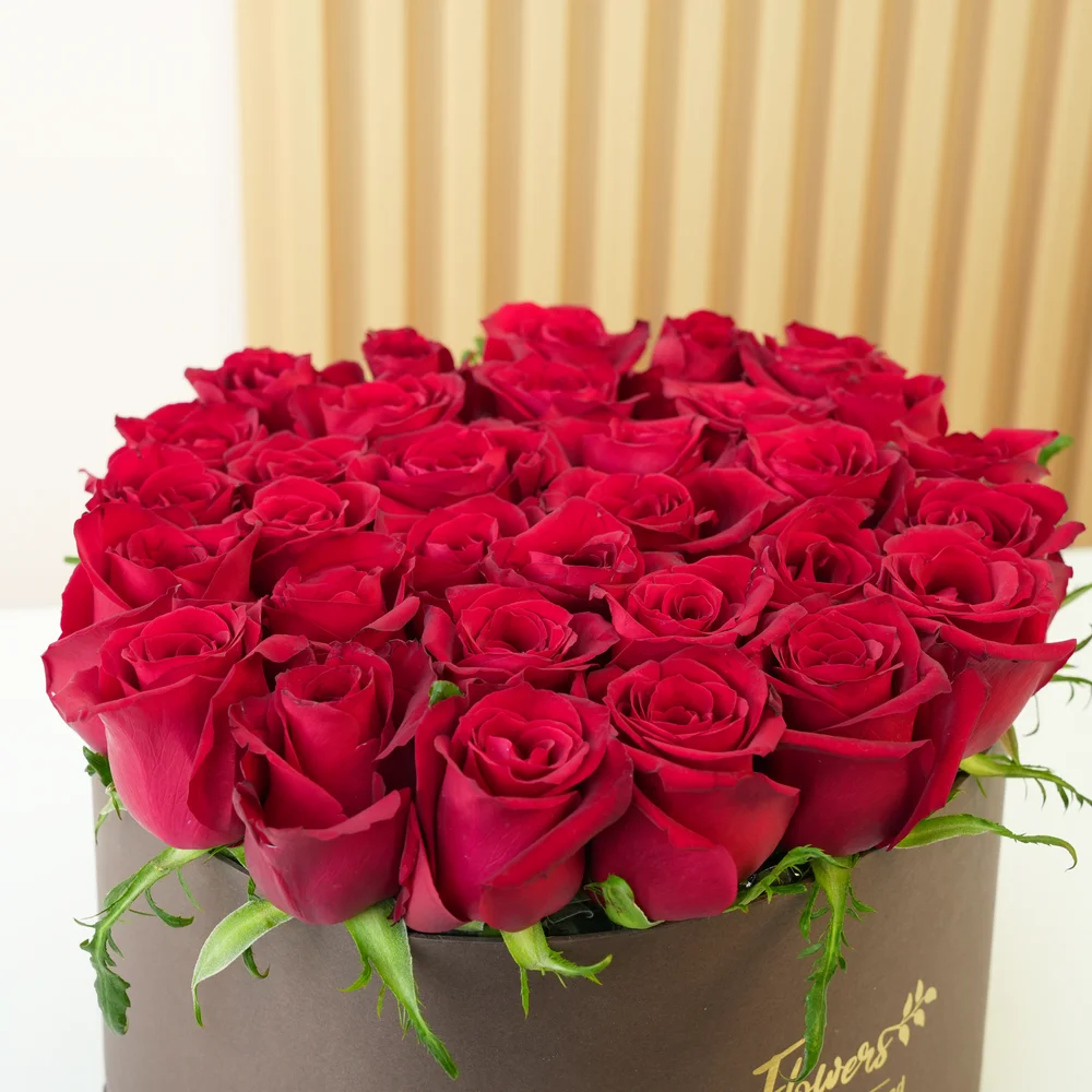 30 red roses with fillers in a round box.
