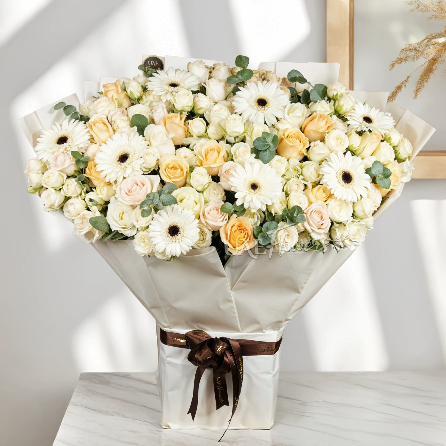 Bouquet of 20 white spray roses, 20 white roses, 10 peach roses and 8 white gerberas with green fillers tied with ribbons.