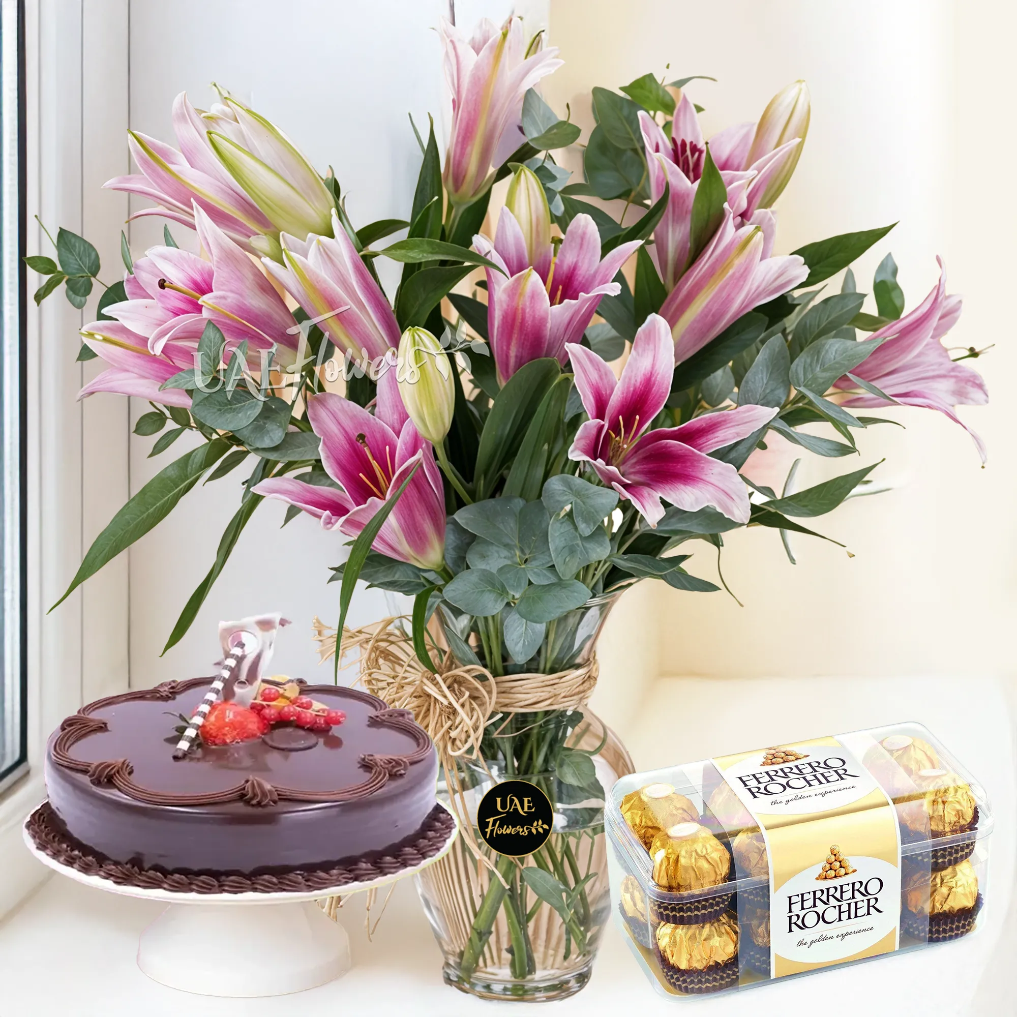 5 pink lilies with fillers in a glass vase, 1 Kg chocolate Cake and 16 pcs Ferrero Rocher Chocolate