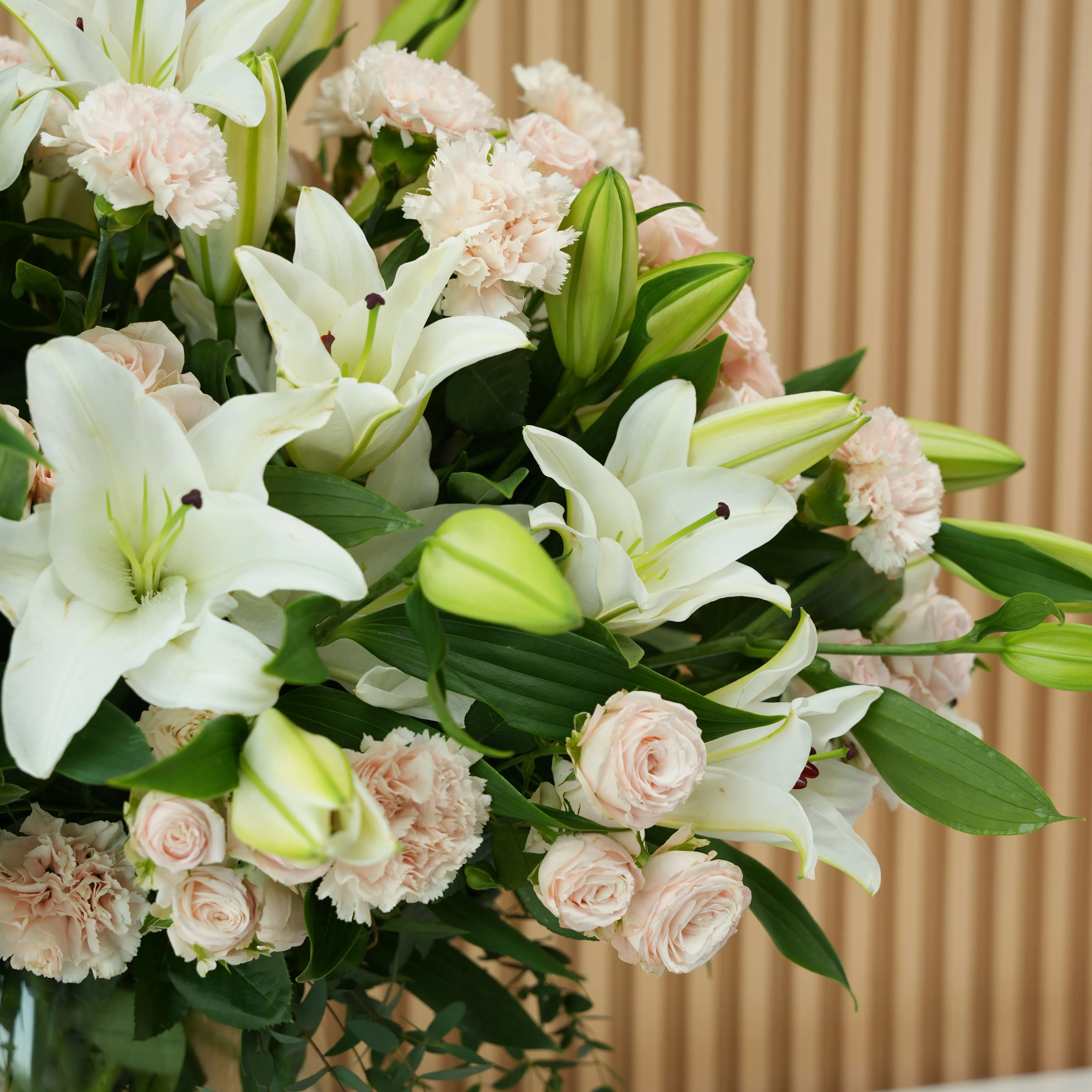 10 white lilies, 20 pink carnations and 20 pink spray roses with fillers in a glass vase.