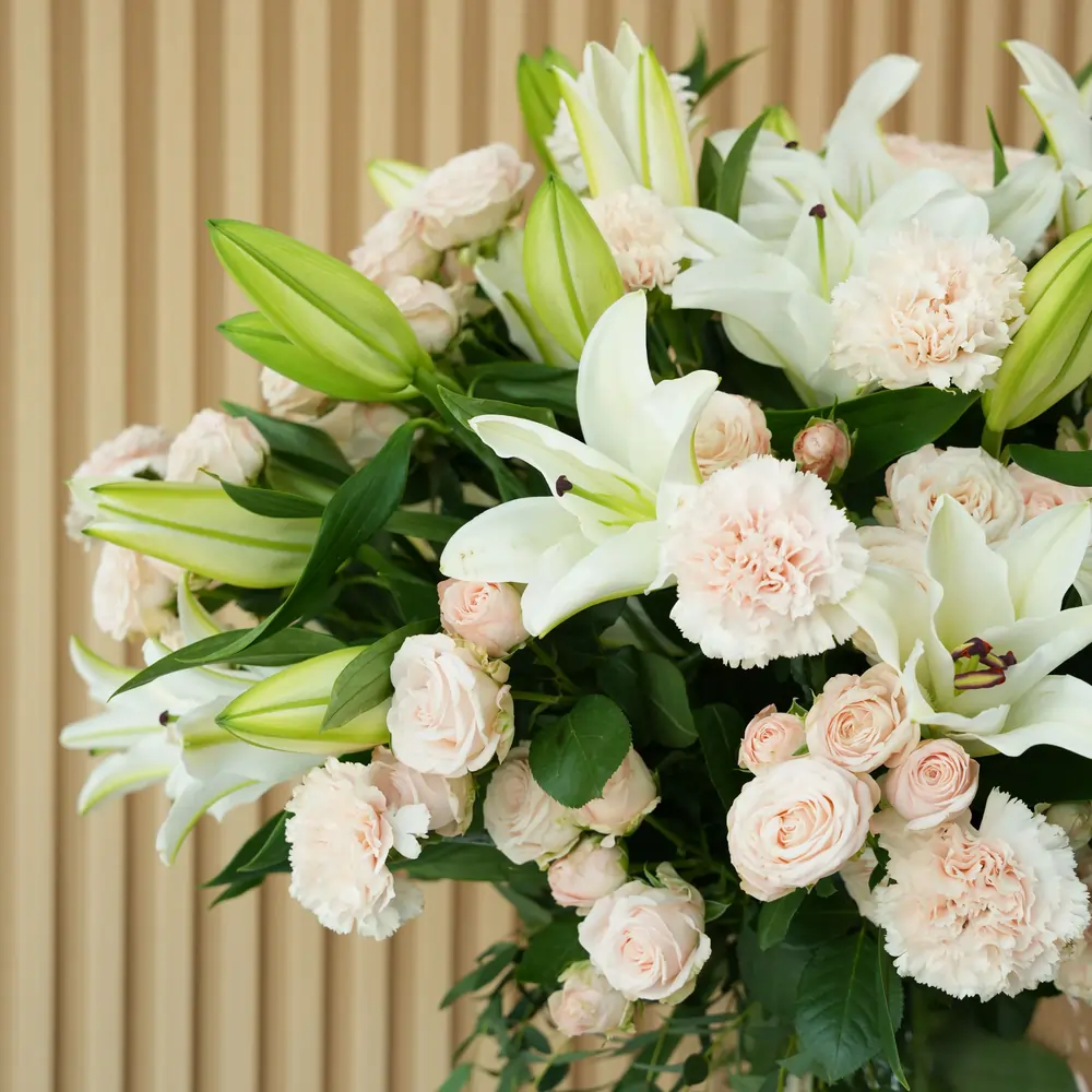 10 white lilies, 20 pink carnations and 20 pink spray roses with fillers in a glass vase.