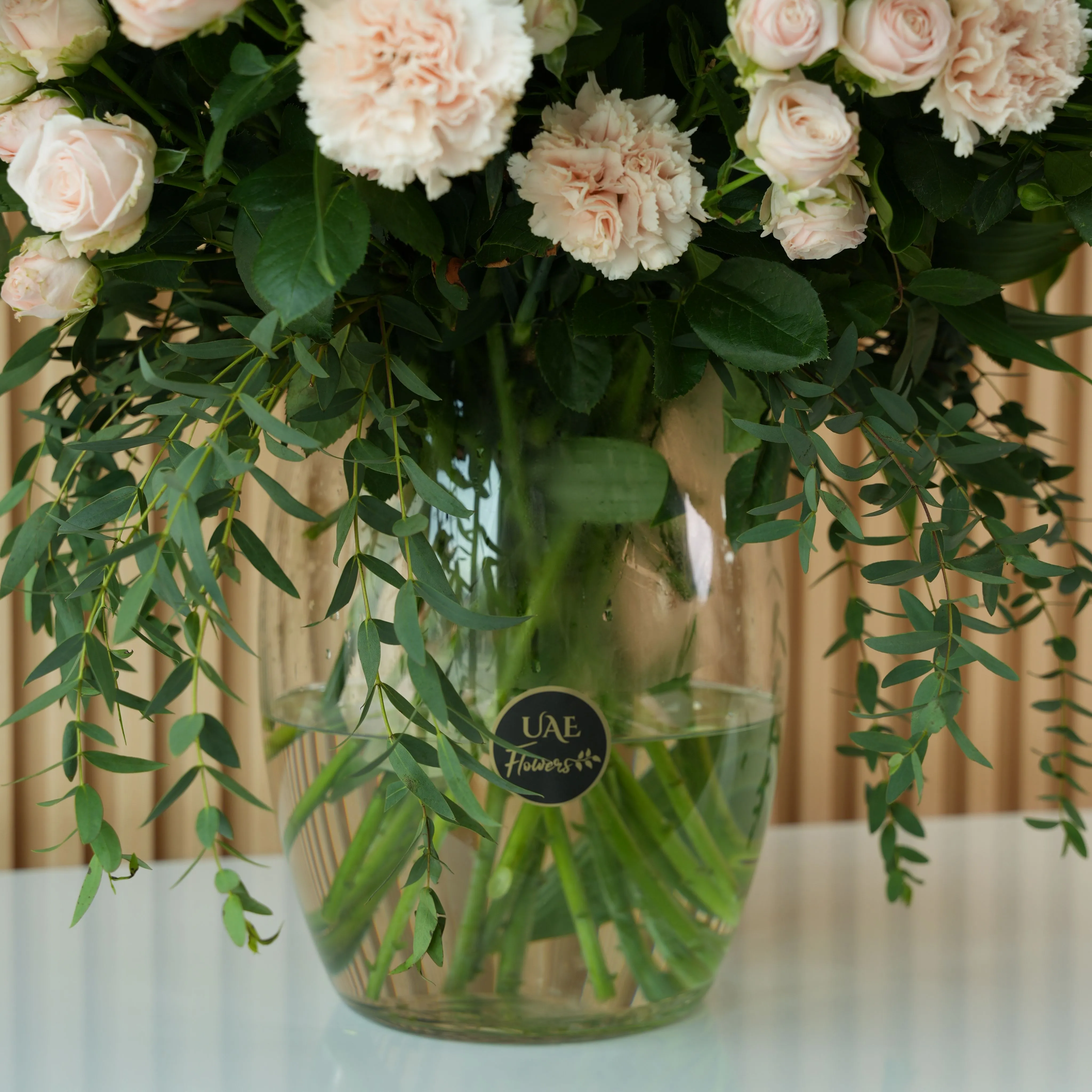 10 white lilies, 20 pink carnations and 20 pink spray roses with fillers in a glass vase.