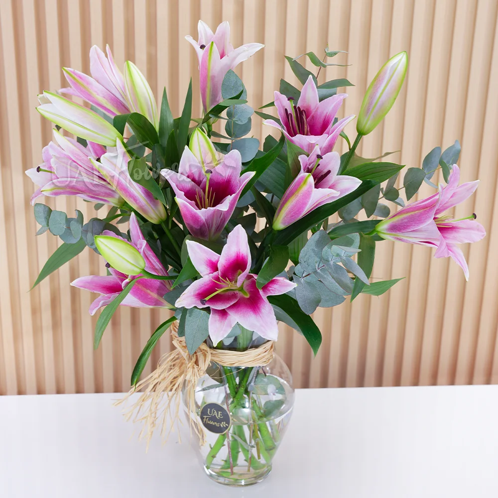 5 pink lilies with green fillers in a glass vase