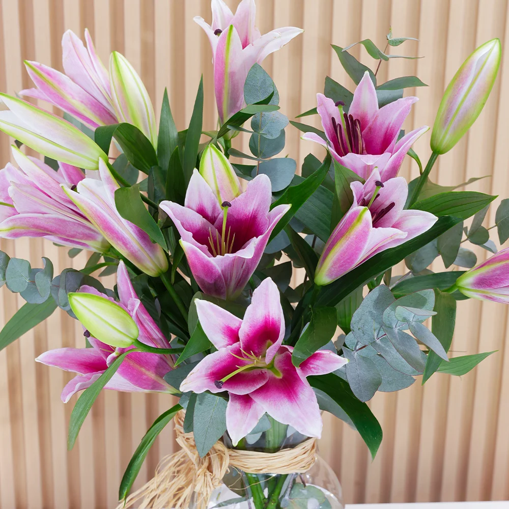5 pink lilies with green fillers in a glass vase