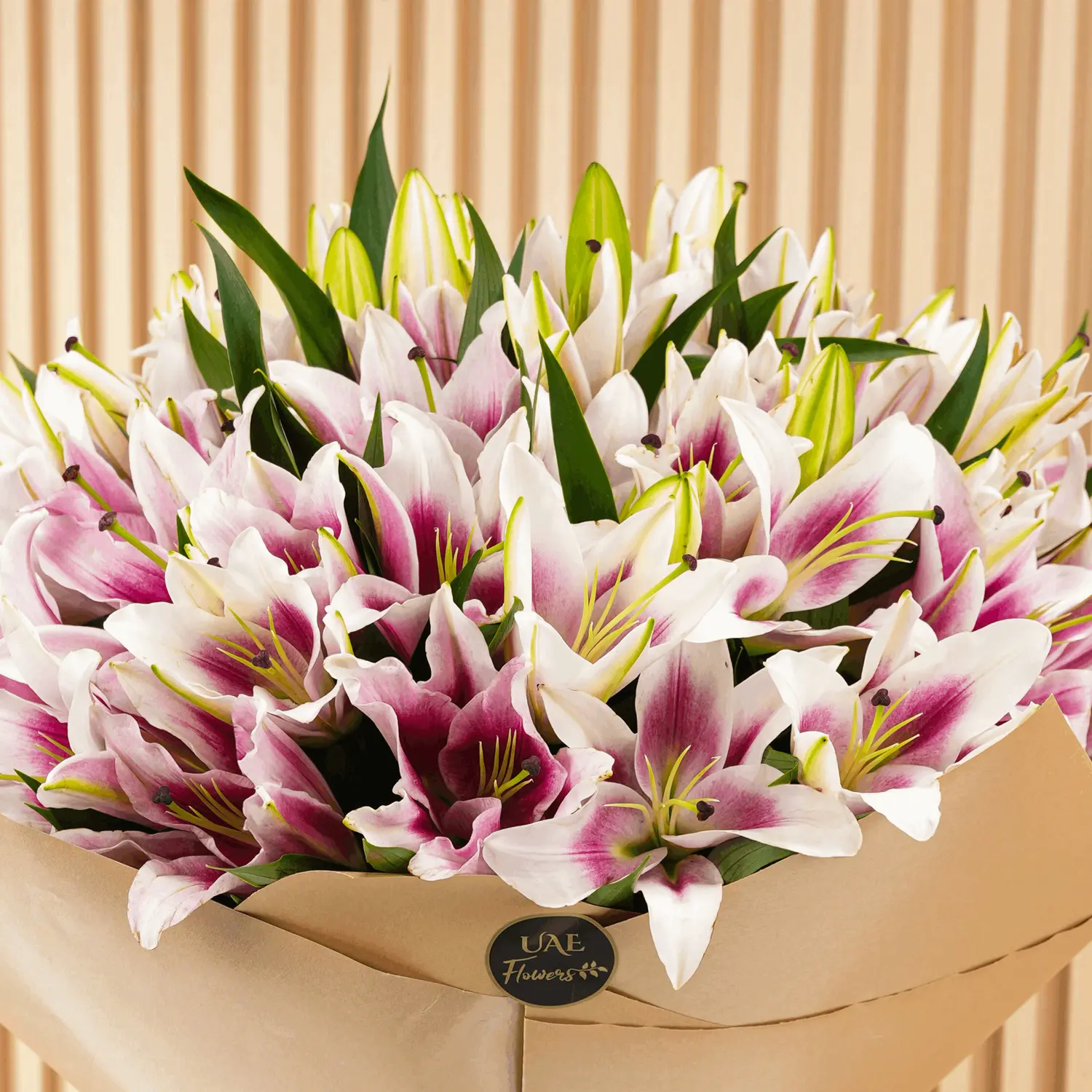 Bouquet of 20 pink lilies with fillers in brown wrapping paper and tied with ribbons.