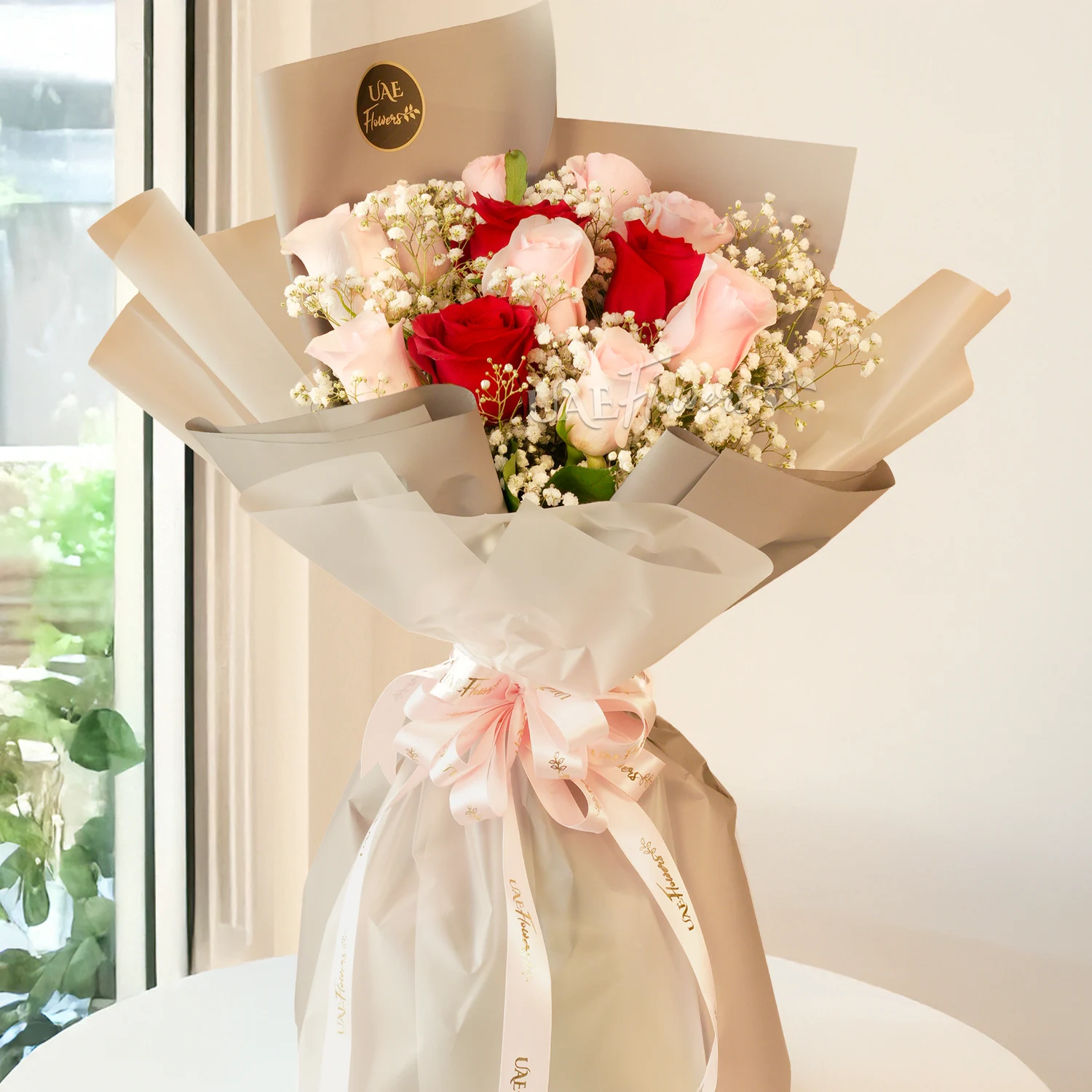 Bouquet, pink roses, red roses with baby's breath fillers in paper packing tied with ribbons.