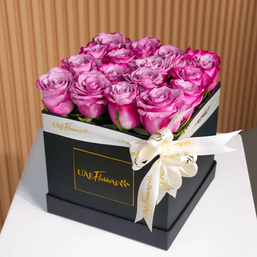 16 stems of Purple roses with fillers in a square black box with a White ribbon