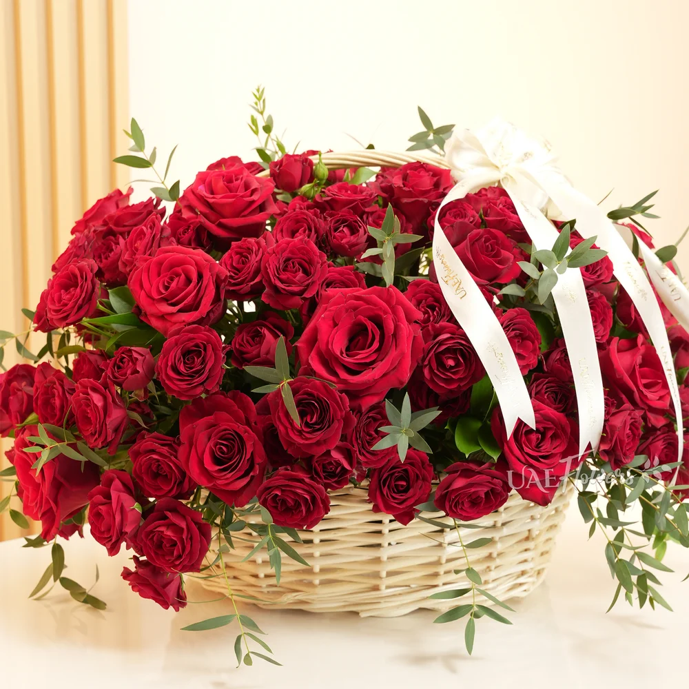 An arrangement of 20 red roses and 10 red spray roses with green fillers in a basket.