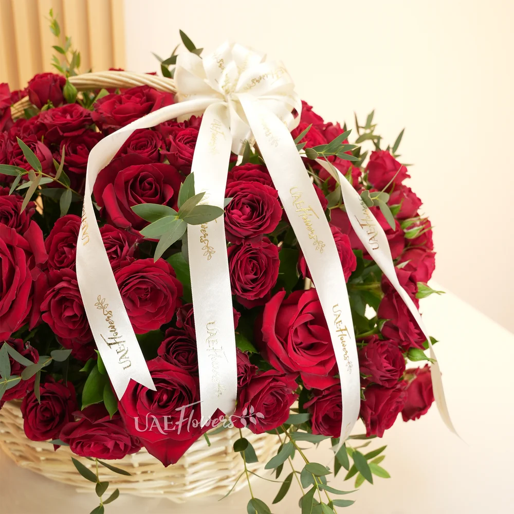 An arrangement of 20 red roses and 10 red spray roses with green fillers in a basket.