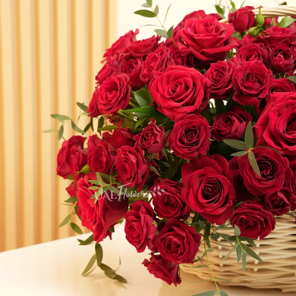 An arrangement of 20 red roses and 10 red spray roses with green fillers in a basket.
