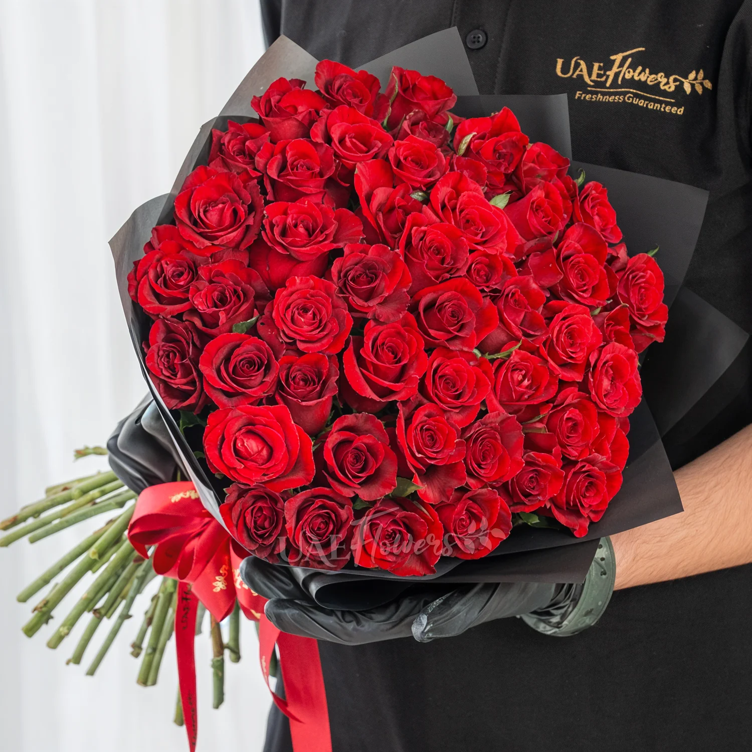 Bouquet of 40 red roses in paper packing hand-tied with ribbons.