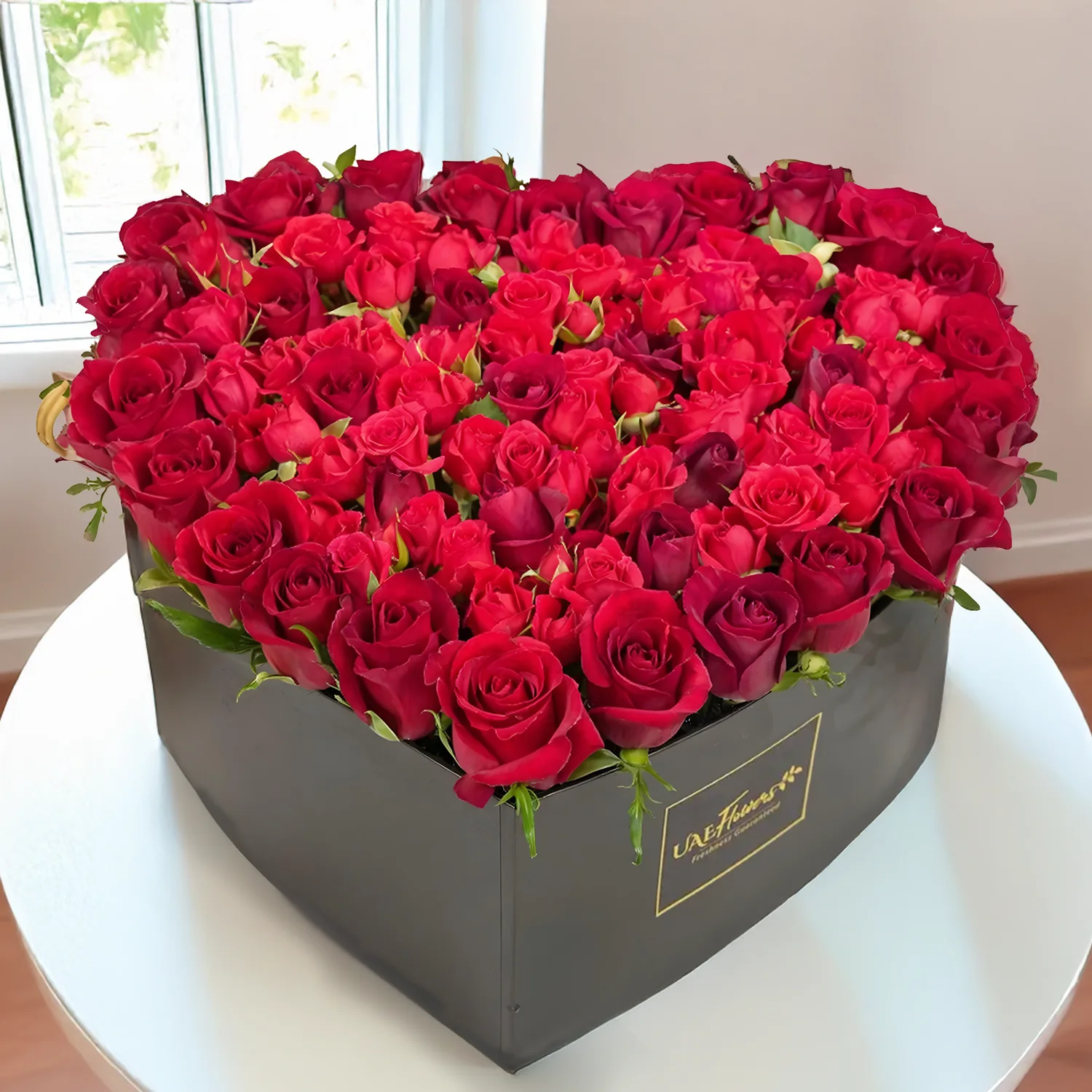 25 red roses and 7 stems of spray roses nicely arranged in a black heart-shaped box.