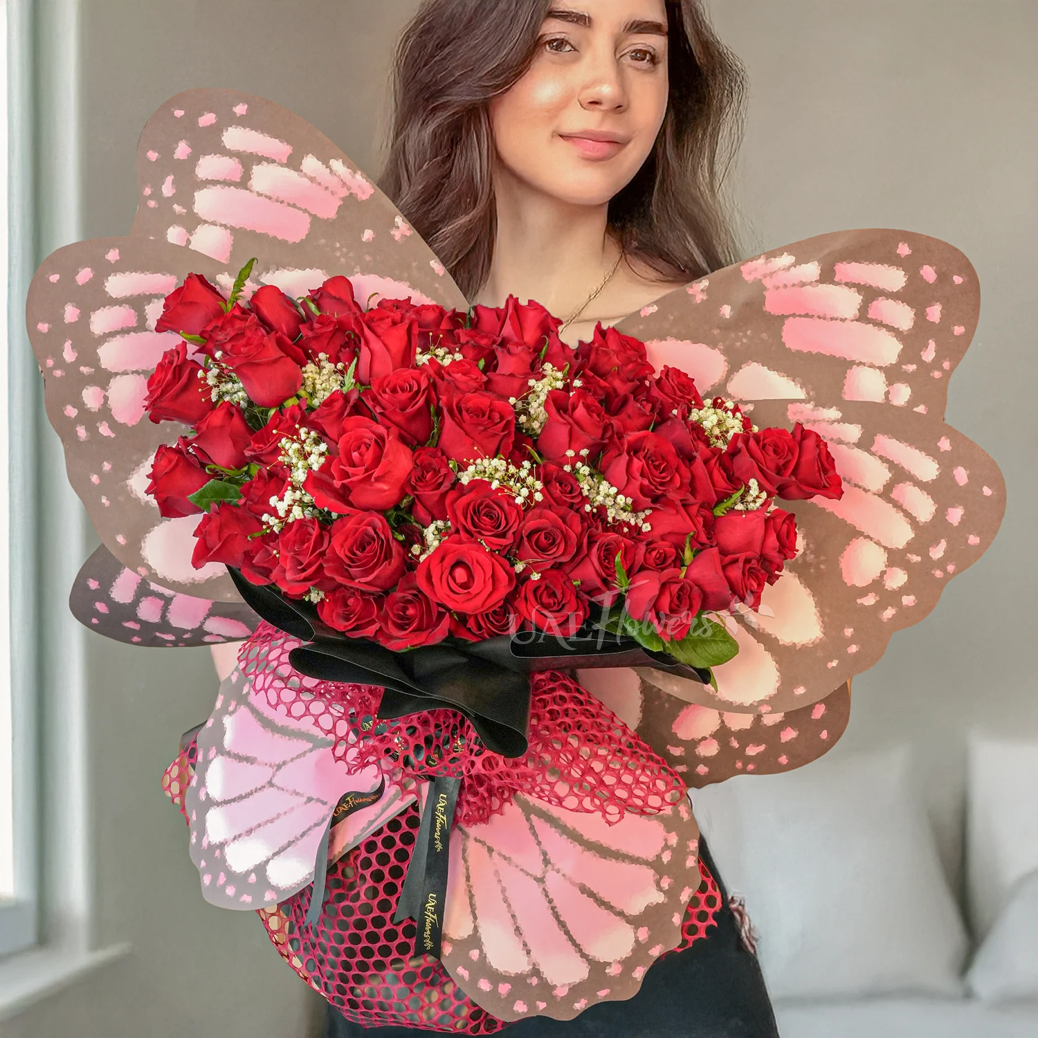 Butterfly bouquet of 50 Red Roses with baby's breath & green fillers tied with ribbons.