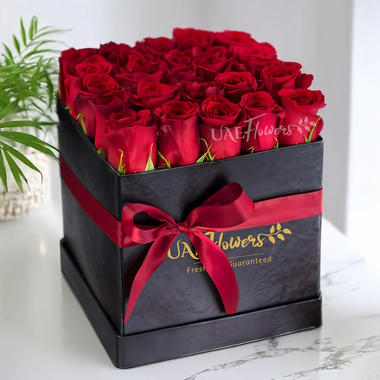20 stems of red roses with fillers in a cube black box with a red ribbon.
