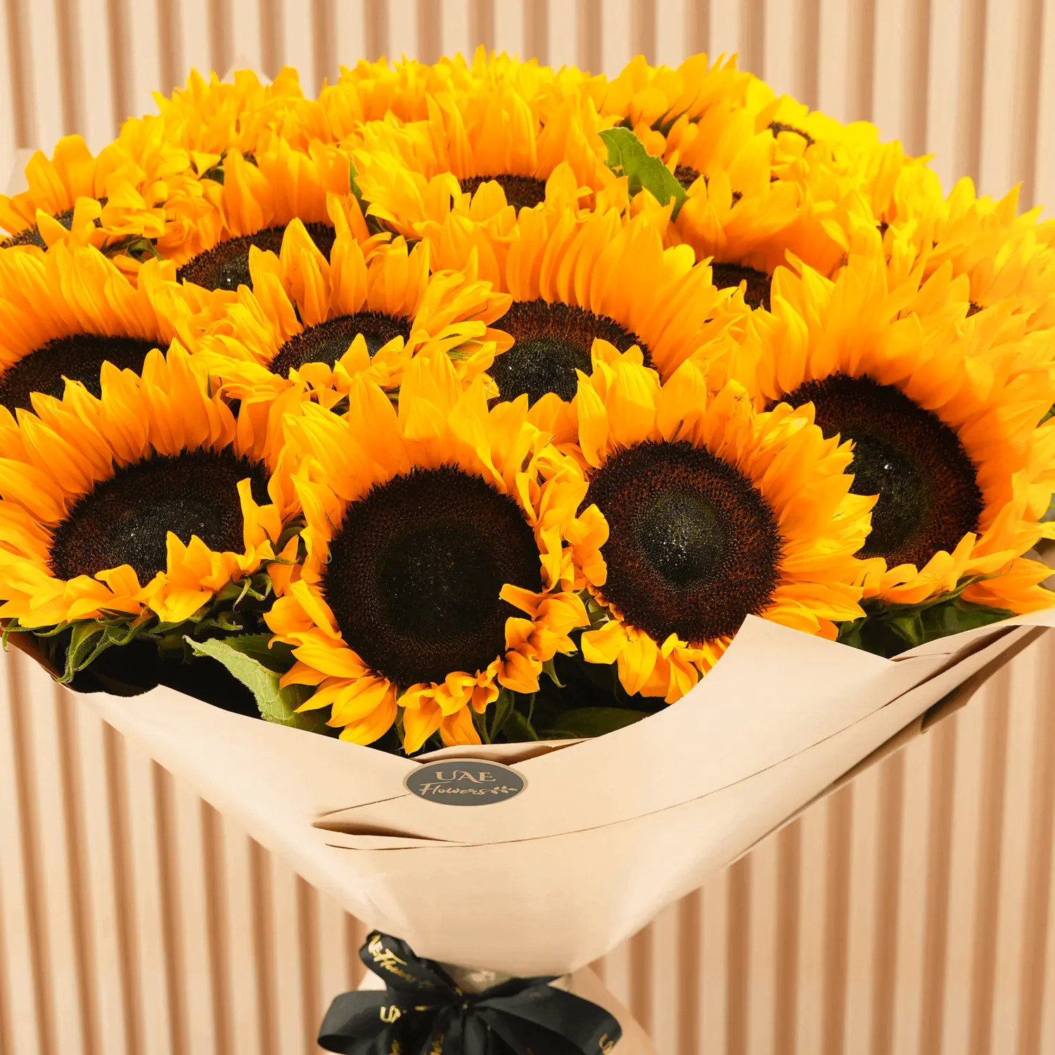 Bouquet of 20 sunflowers with fillers in brown wrapping paper and tied with ribbons.