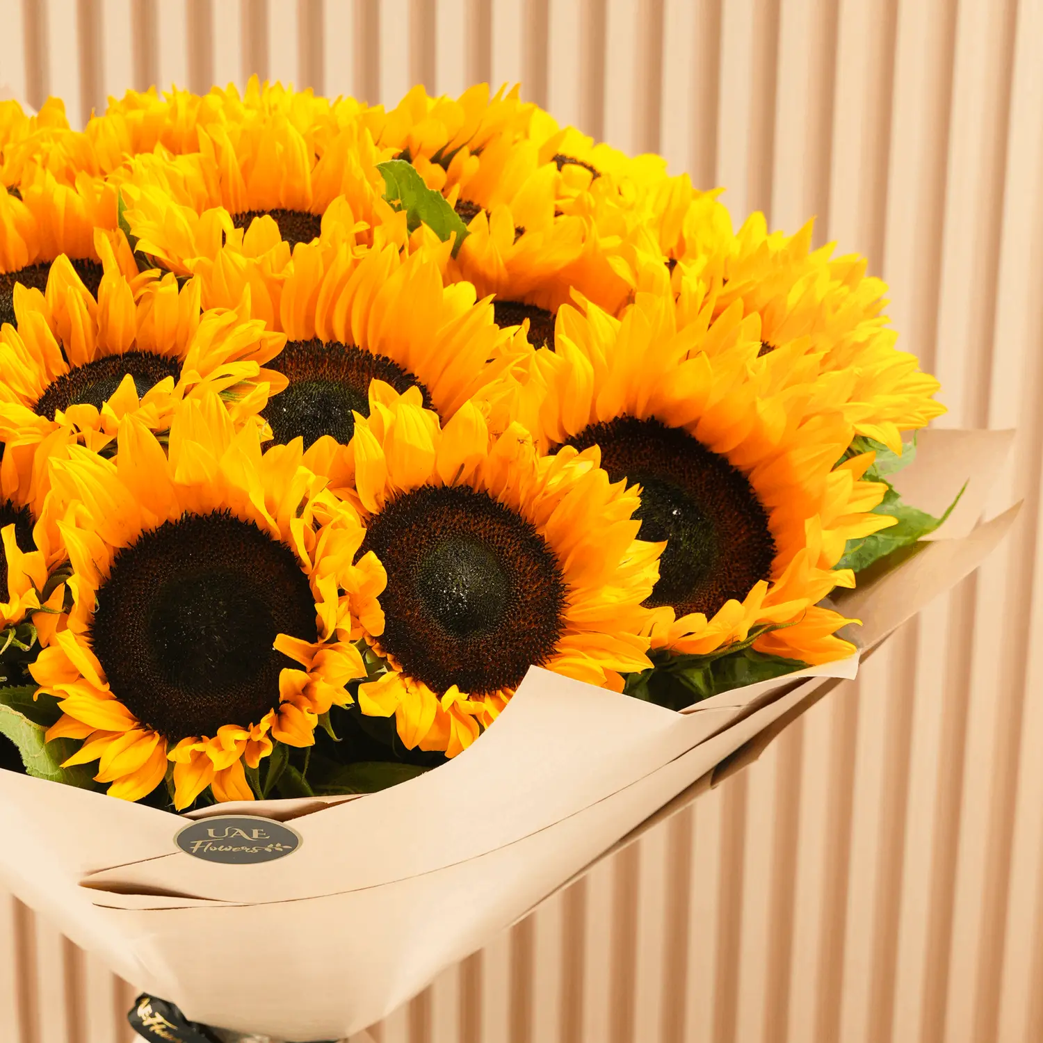Bouquet of 20 sunflowers with fillers in brown wrapping paper and tied with ribbons.