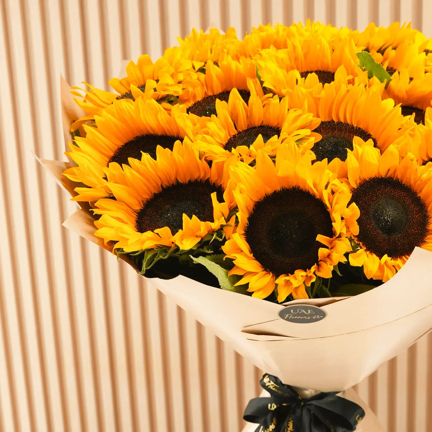 Bouquet of 20 sunflowers with fillers in brown wrapping paper and tied with ribbons.