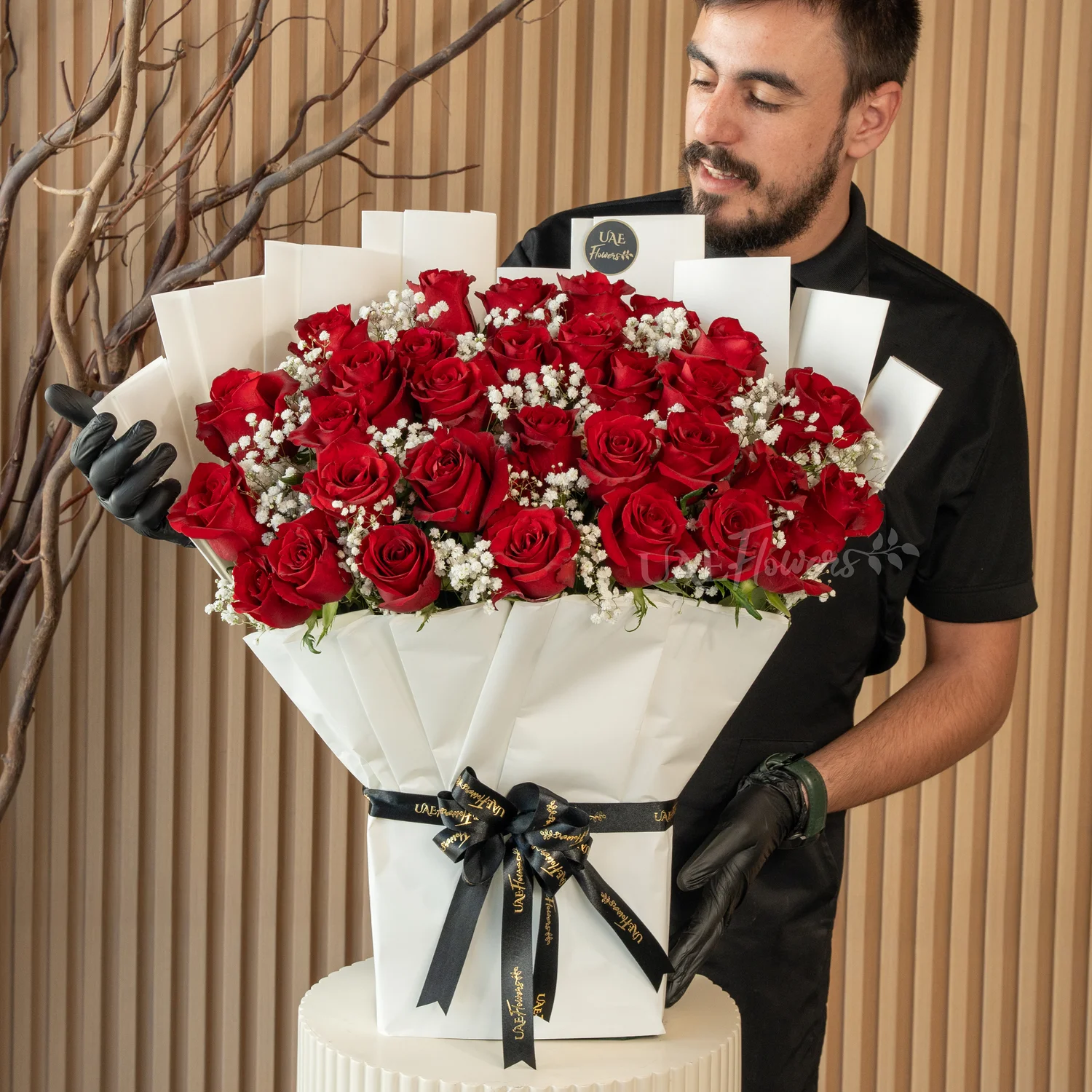 Bouquet of 30 red roses with green fillers in paper packing tied with ribbons.