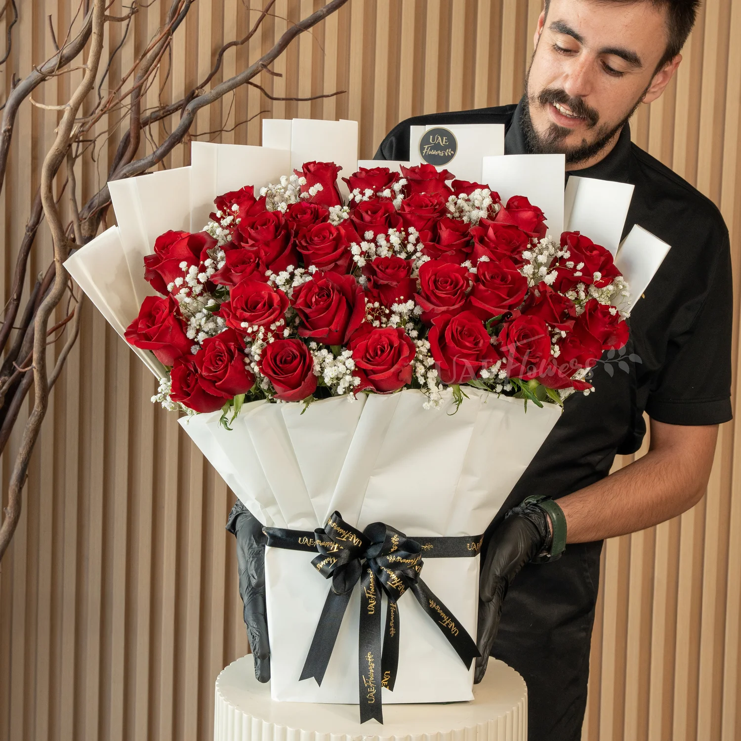 Bouquet of 30 red roses with green fillers in paper packing tied with ribbons.