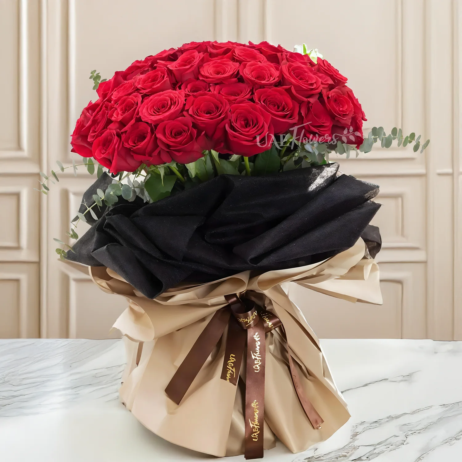 Bouquet of 40 red roses with eucalyptus leaf in black and brown paper packing tied with brown ribbons.