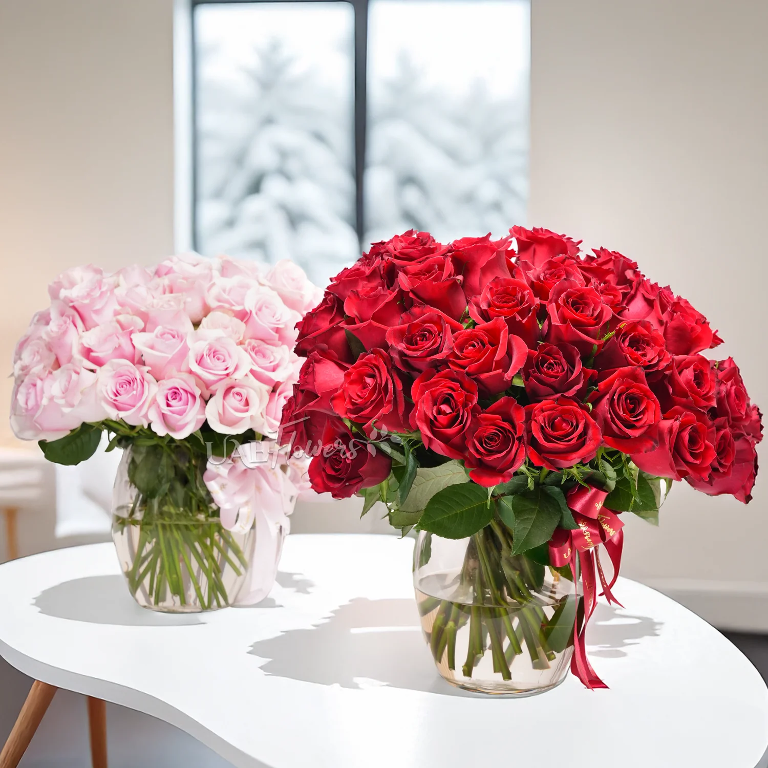 Separate vase arrangements of 50 red roses with green fillers and 50 pink roses with green fillers.