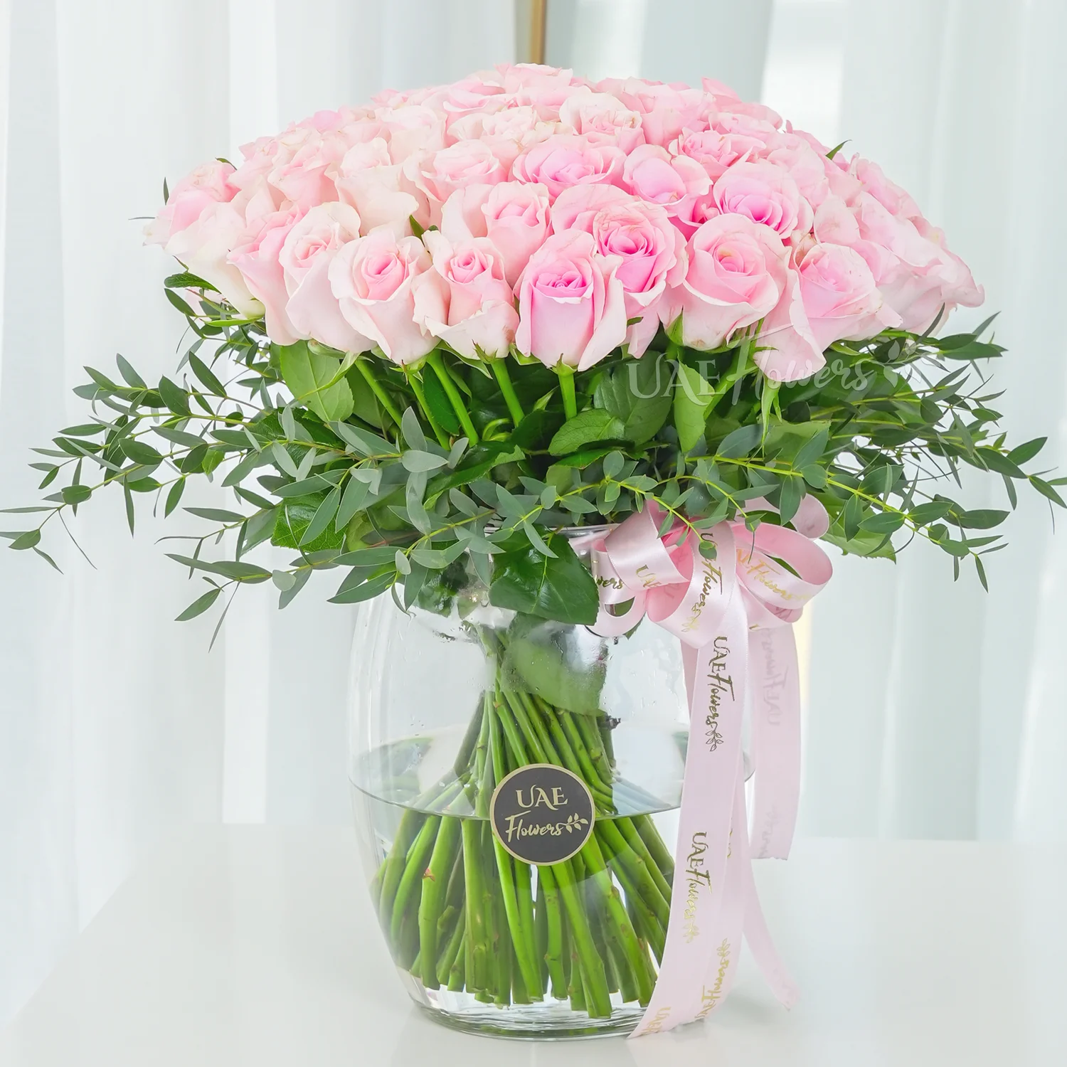 A vase arrangement of 40 pink roses with green fillers and tied with pink ribbons.
