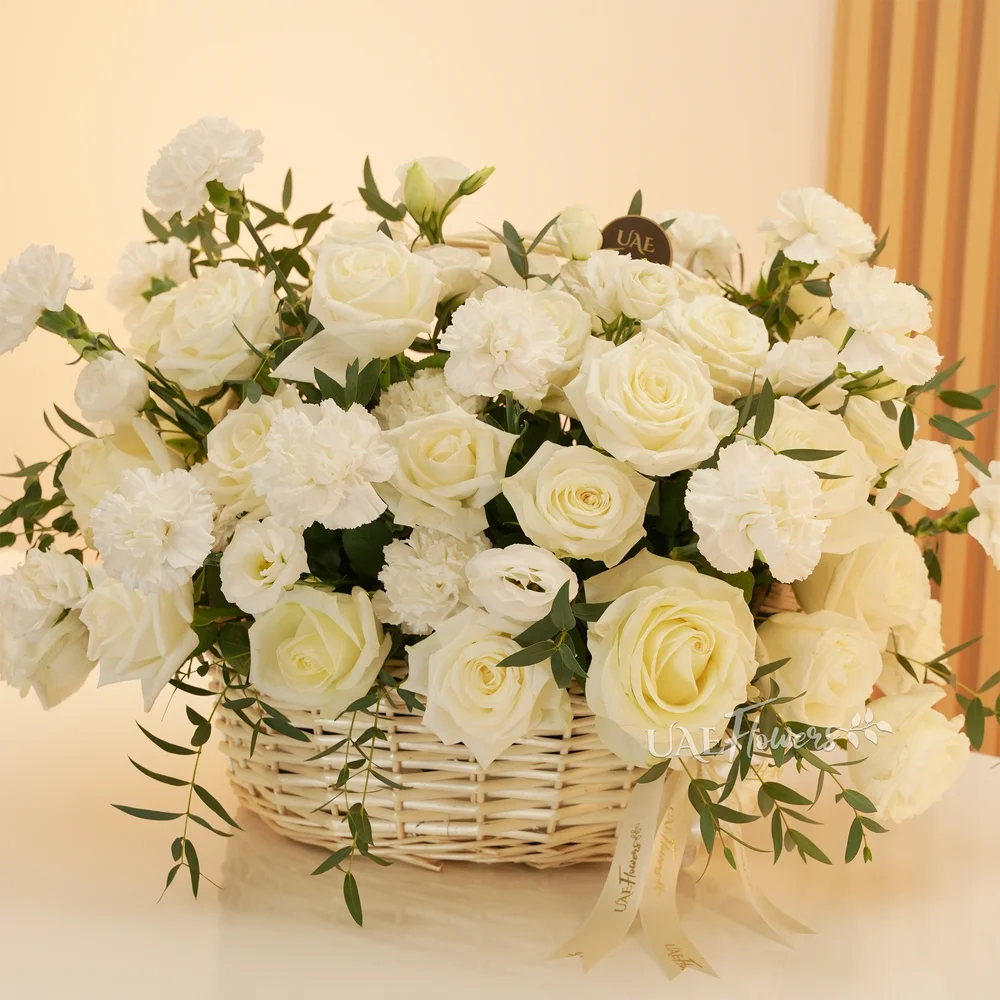 A basket arrangement of 15 white carnations and 15 white roses and fillers.