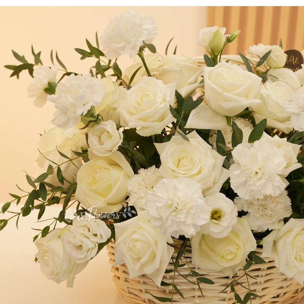 A basket arrangement of 15 white carnations and 15 white roses and fillers.