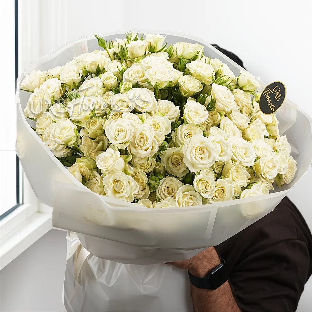 Bouquet of 40 White spray Roses with green fillers in white wrapping paper tied with ribbon.